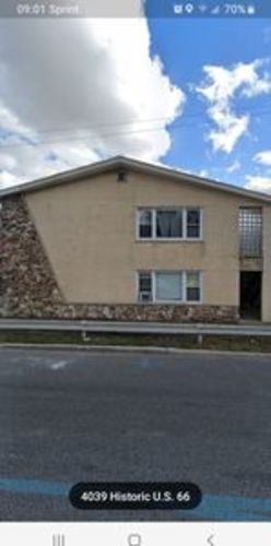 A building with a stone wall and a brown roof.