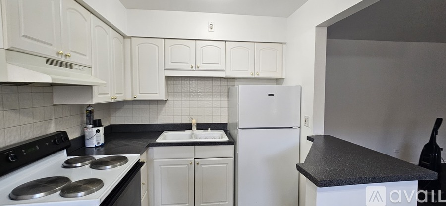 A kitchen with white cabinets and a black countertop.
