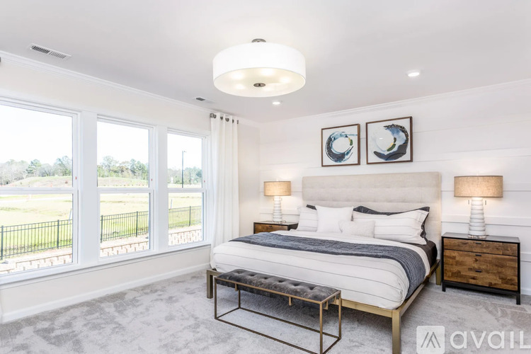 A bedroom with a large bed, two lamps, and two framed pictures on the wall.