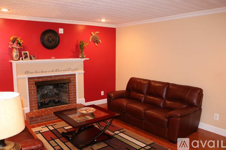 A living room with a fireplace and a brown leather couch.