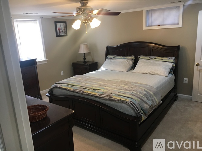 A bedroom with a large bed, a ceiling fan, and a basket on a table.