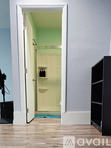 A bathroom with a glass shower door and a white door frame.