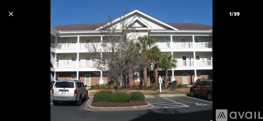 A building with a white facade and a tree in front of it.