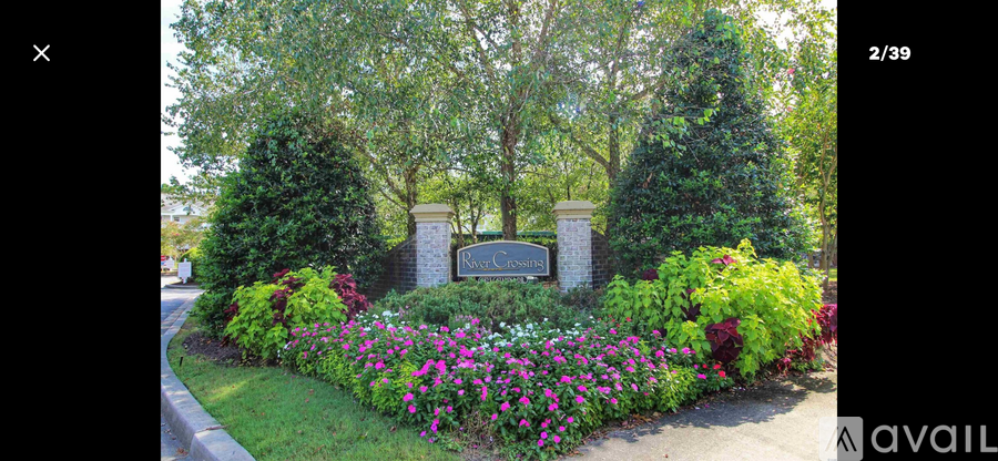 A garden with a sign that says "AVAIL" in front of a stone pillar.