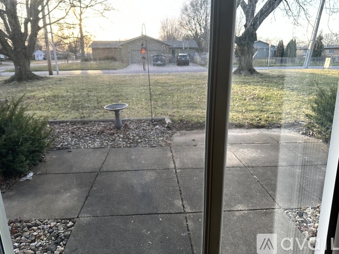 A view from a window looking out to a residential area with a mailbox and trees.
