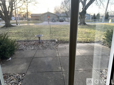 A view from a window looking out to a residential area with a mailbox and trees.