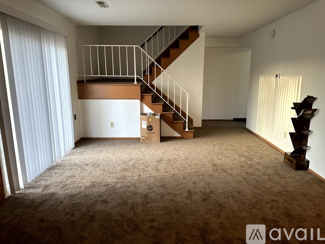 A spacious room with a staircase and a carpeted floor.