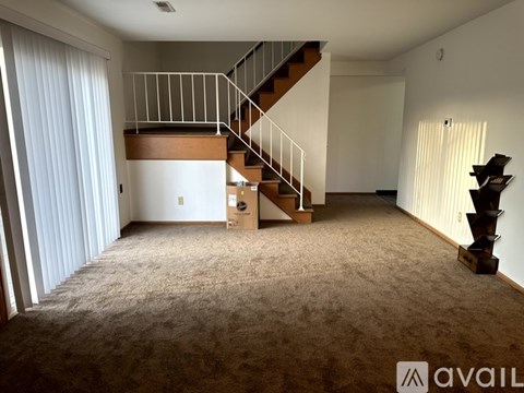A spacious room with a staircase and a carpeted floor.
