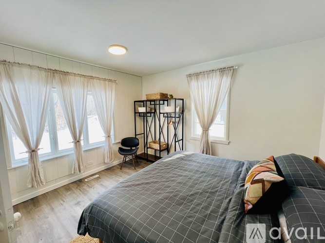 A bedroom with a large bed and a chair by the window.