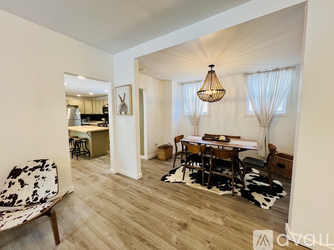 A room with a dining table and chairs in the foreground and a kitchen in the background.