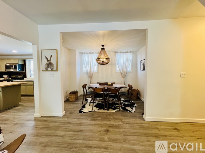 A dining area with a table set for four and a chandelier hanging from the ceiling.