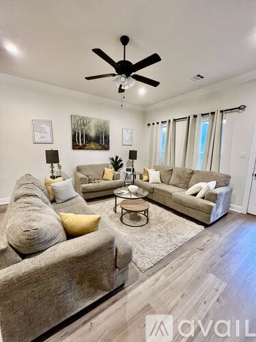 A living room with a grey couch, a coffee table, and a ceiling fan.