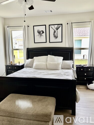 A bedroom with a large bed, a bench, and two pictures on the wall.
