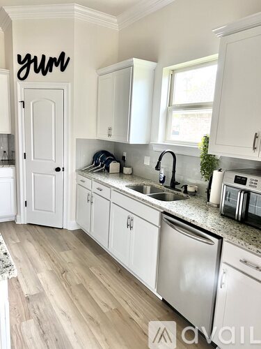 A kitchen with white cabinets and a wooden floor.