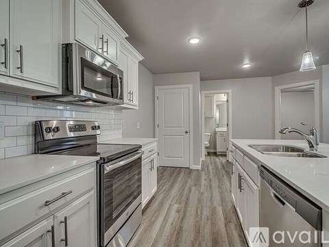 A kitchen with white cabinets and a stove top oven.