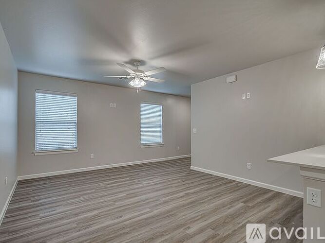 A spacious room with a ceiling fan and wooden flooring.