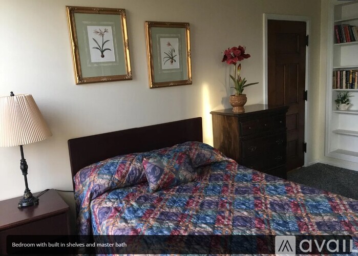 A bedroom with a bed, lamp, and two framed pictures on the wall.