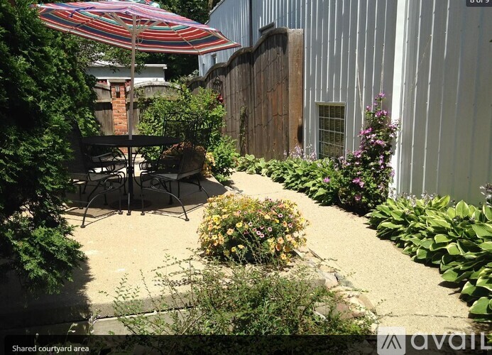 A patio area with a table and chairs under a striped umbrella.