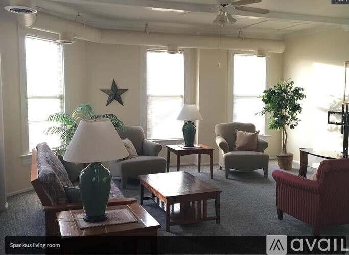 A living room with a sofa, armchair, and a table with a green vase on it.