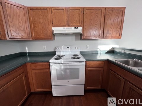 A white stove in a kitchen with wooden cabinets.