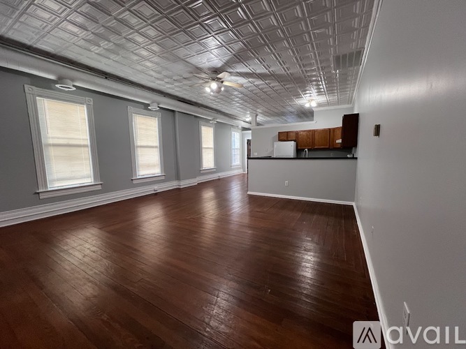 A spacious room with wooden floors and a ceiling of square tiles.