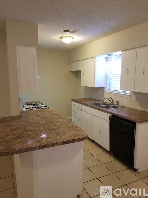 A kitchen with a brown counter top and white cabinets.