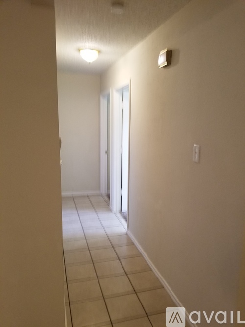 A hallway with a tiled floor and a door at the end.