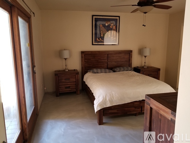 A bedroom with a bed, two nightstands, and a ceiling fan.