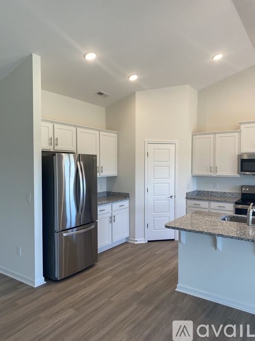 A kitchen with a stainless steel refrigerator and wooden flooring.