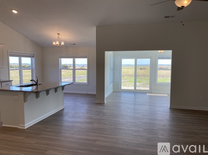 A spacious room with wooden floors and a large window overlooking the outdoors.