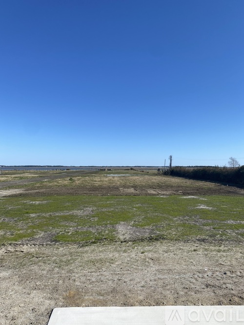 A vast open field with a clear blue sky above.