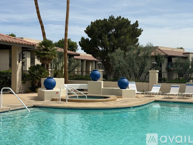 A pool with a few chairs and two large blue balls.