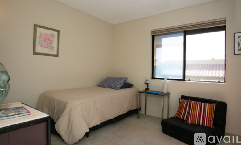 A bedroom with a bed, a chair, and a window.