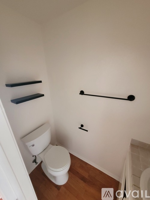 A white toilet in a small bathroom with a black grab bar.