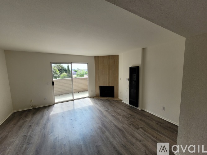 A spacious room with wooden flooring and a large window.