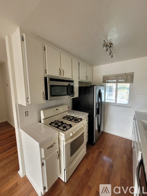 A kitchen with white cabinets and a black fridge.