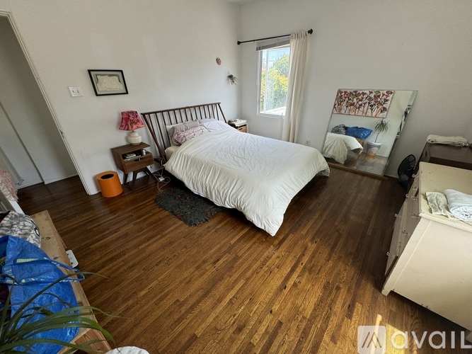 A bedroom with a large bed and wooden floors.
