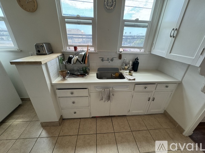 A kitchen with white cabinets and a window overlooking a cityscape.