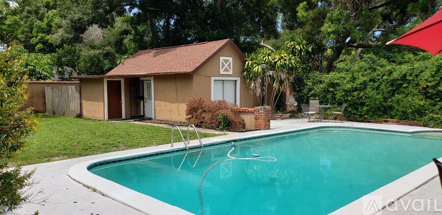A pool in a backyard with a small house and a flag.