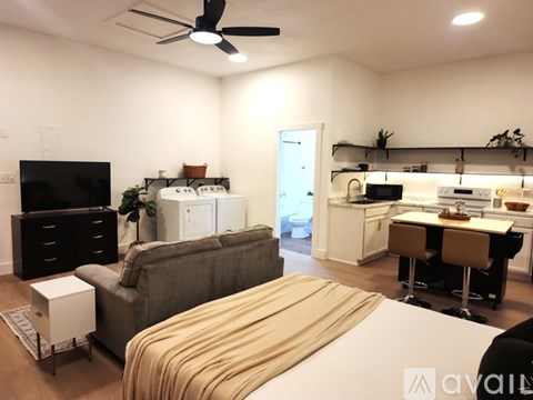 A living room with a grey couch and a white bed.