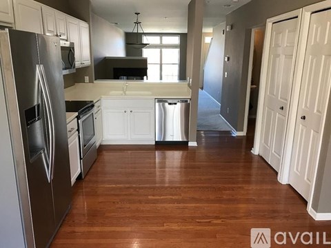 A kitchen with white cabinets and a wooden floor.