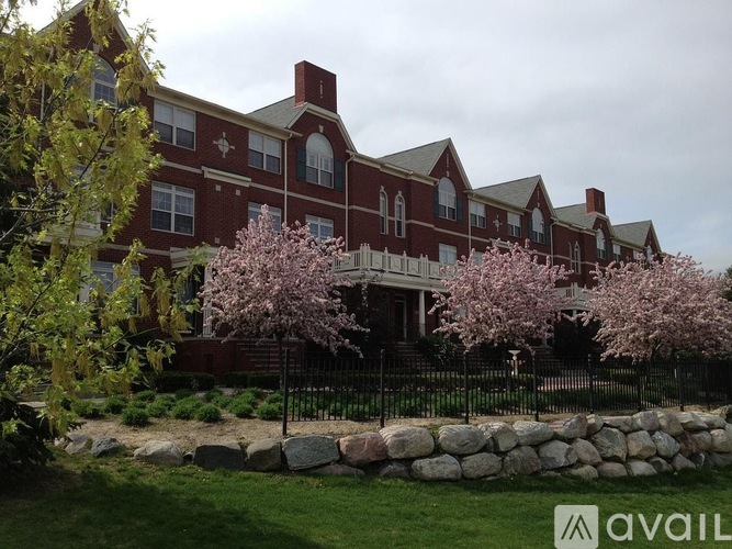 A large red brick building with a black fence and a stone wall in front.