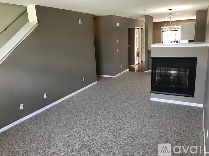 A spacious living room with a fireplace and a staircase.