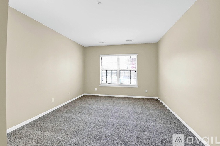 A spacious room with a carpeted floor and a window.