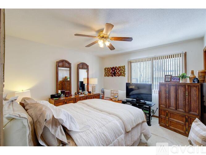 A bedroom with a large bed, a flat screen TV, and a wooden cabinet.