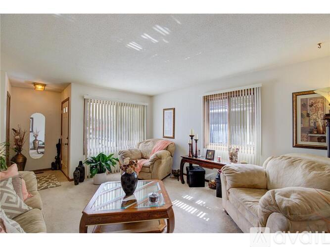 A living room with a couch, coffee table, and plants.