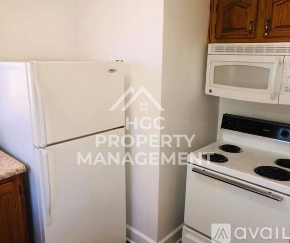 A kitchen with a white refrigerator, white stove, and a white microwave above the stove.