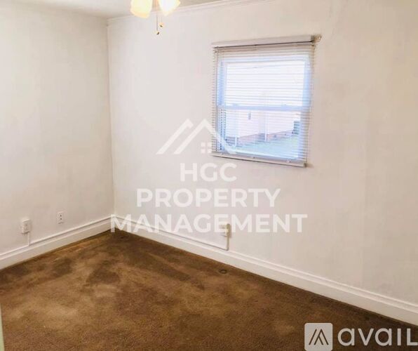 A room with a window and a carpeted floor.