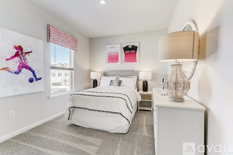 A bedroom with a white bed and a painting of a person jumping on the wall.