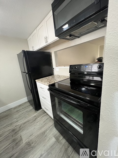 A black fridge and oven in a kitchen with a microwave above it.